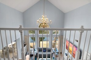 A high-ceiling room with a chandelier, a large window, and a view of the outdoors.
