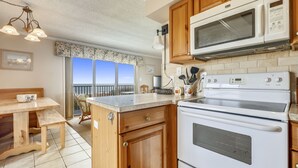 Eine Küche mit Holzausstattung, einer Mikrowelle, einem Backofen und einem Essbereich mit Tisch und Stühlen.