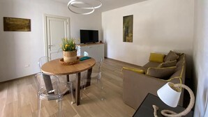 A modern living room with a wooden dining table, clear chairs, a sofa, and a TV. - Villa Malepè with private pool (MELENDUGNO)
