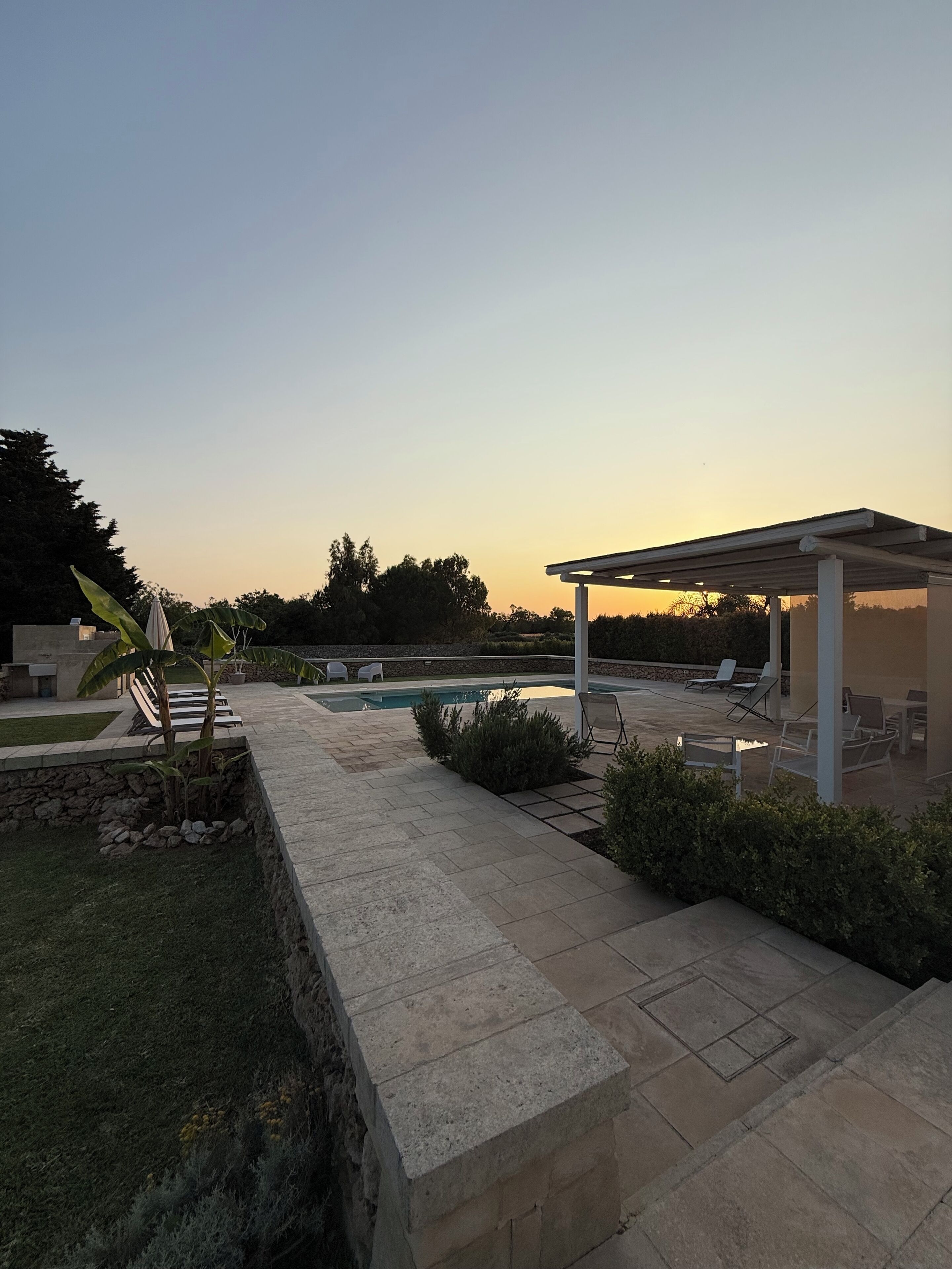 A patio area with a pool, lounge chairs, and a covered seating area.