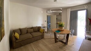 Una sala de estar moderna con un sofá, una mesa de comedor con sillas y una lámpara de techo.