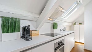 Een moderne keuken met dakraam, witte kasten en een koffieapparaat.