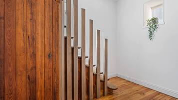 A wooden staircase with a white wall and a small window with a plant.