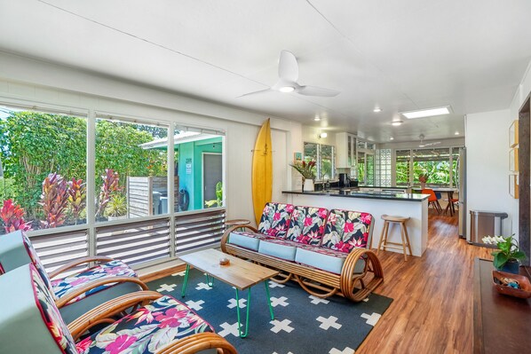 A modern living area with a sofa, chairs, a table, and a kitchen in the background.