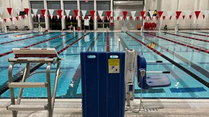 Une piscine intérieure avec des couloirs de nage, un plot de départ et un poste de surveillance pour le sauveteur.