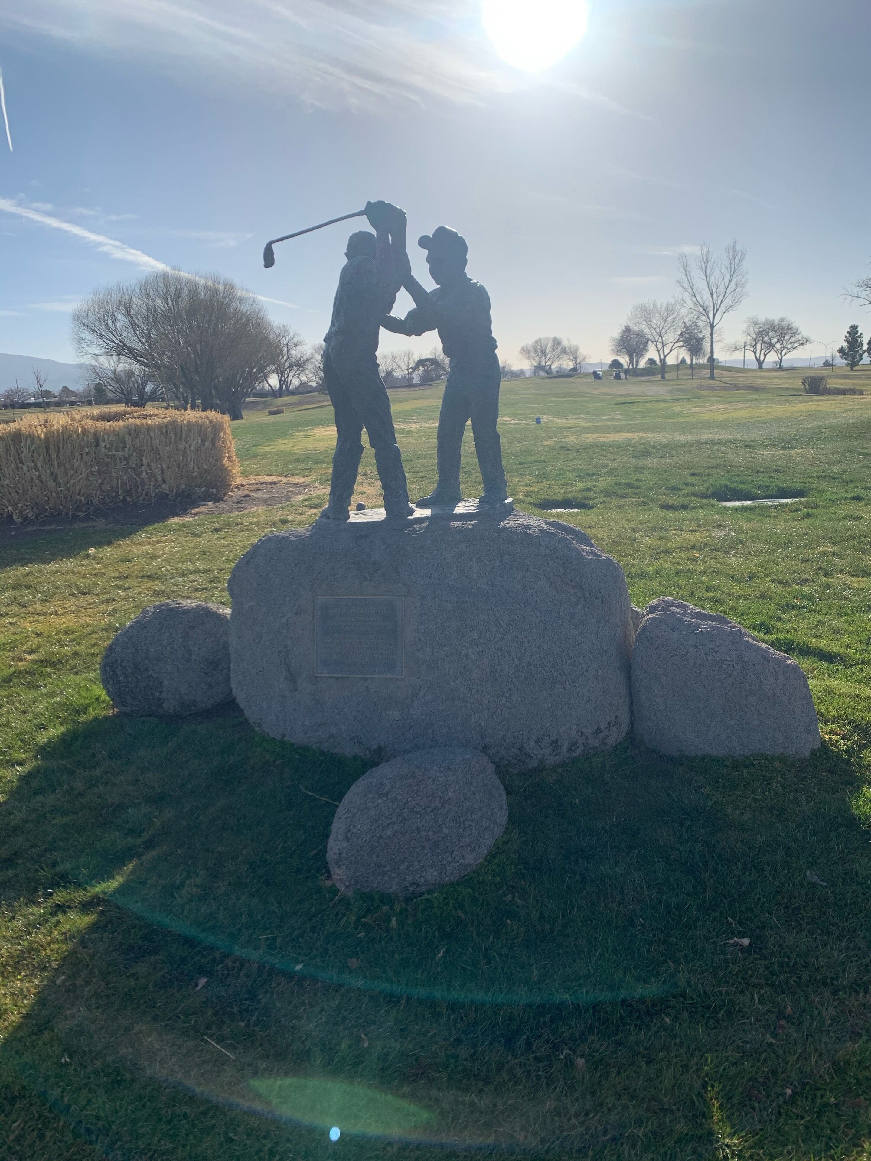Una escultura de dos figuras sobre un pedestal de piedra en un campo cubierto de hierba.