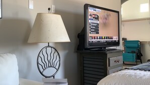 Une chambre d’hôtel avec un lit, un bureau doté d’une lampe, une télévision et une chaise.
