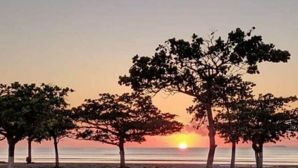 A beach scene with trees and a sunset. - House with pool and barbecue in Caraguatatuba, in a gated community with Wi-Fi. (SP)