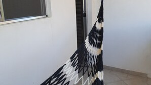 A hammock hanging between two white walls with a window and a door. - House with pool and barbecue in Caraguatatuba, in a gated community with Wi-Fi. (SP)