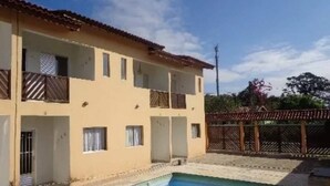A two-story building with a swimming pool in front. - House with pool and barbecue in Caraguatatuba, in a gated community with Wi-Fi. (SP)