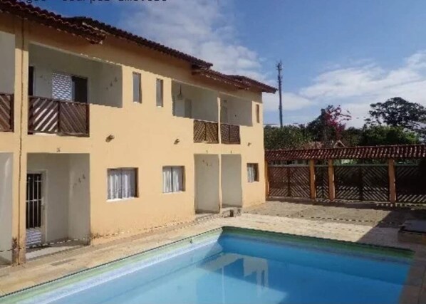 Un bâtiment à deux étages avec une piscine devant.
