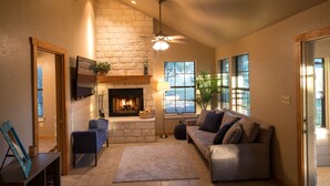 A cozy living room with a fireplace, comfortable seating, and large windows.