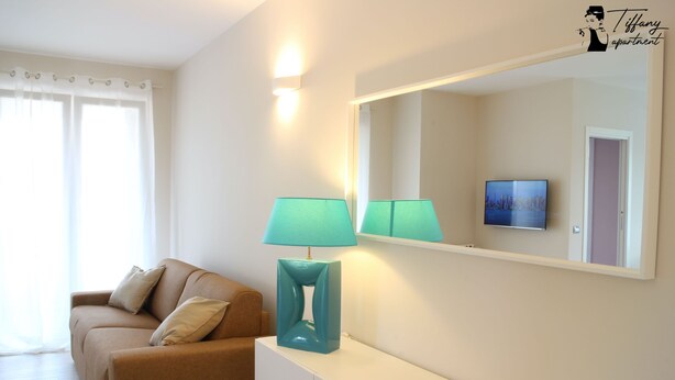 Un salon avec un canapé, une lampe et un téléviseur.
