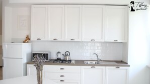 Une cuisine moderne avec des meubles blancs, un four à micro-ondes, une cuisinière à gaz et un évier.