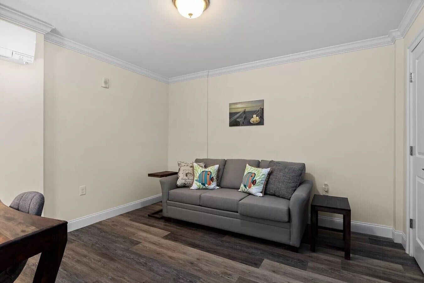 A living room with a grey sofa, a small table, and a wooden floor.