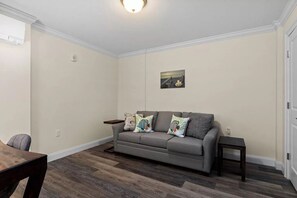 A living room with a grey sofa, a small table, and a wooden floor.