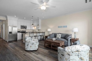 A modern kitchen with white cabinets, stainless steel appliances, and pendant lighting.