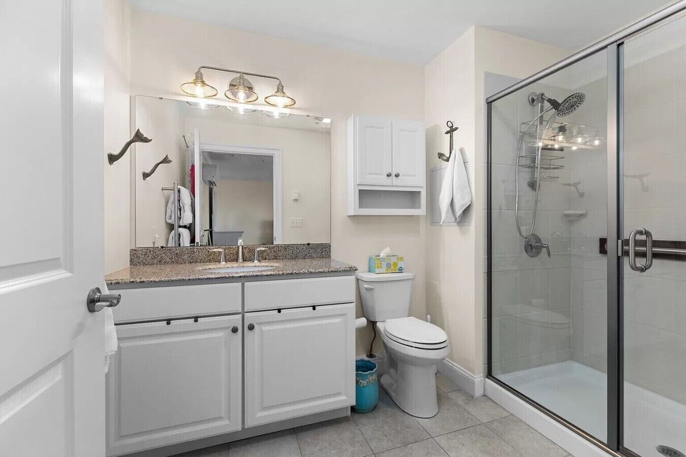 A modern bathroom with a double vanity, a glass shower enclosure, and a toilet.