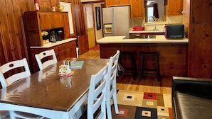 Cocina compacta con armarios de madera, un refrigerador, un microondas y un comedor con mesa y sillas.