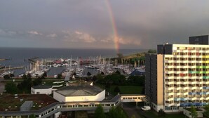 A marina with boats, a building with a flat roof, and a rainbow in the sky. - Cottage with fireplace, near the beach, dogs welcome, kitchen is new, fenced  (Damp)