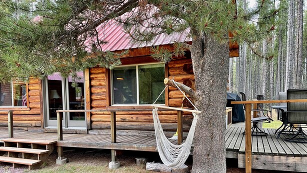 Un chalet rustique doté d’une terrasse, d’un hamac et de meubles pour se détendre à l’extérieur.