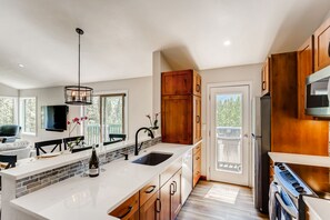 Een moderne keuken met een groot eiland, houten kastjes en een inbouwoven.