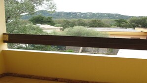 Een balkon met uitzicht op een heuvelachtig landschap en gebouwen.