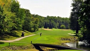 Golfkenttä, jonka poikki kulkee puroa ylittävä silta, ja jonka ympärillä on puita.