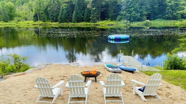 Un cadre idyllique au bord du lac, avec un foyer, des chaises et des canoës.