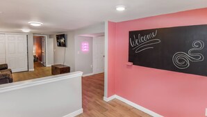 Un interior moderno con una pared de acento rosa, un cartel de bienvenida y un letrero de neón.