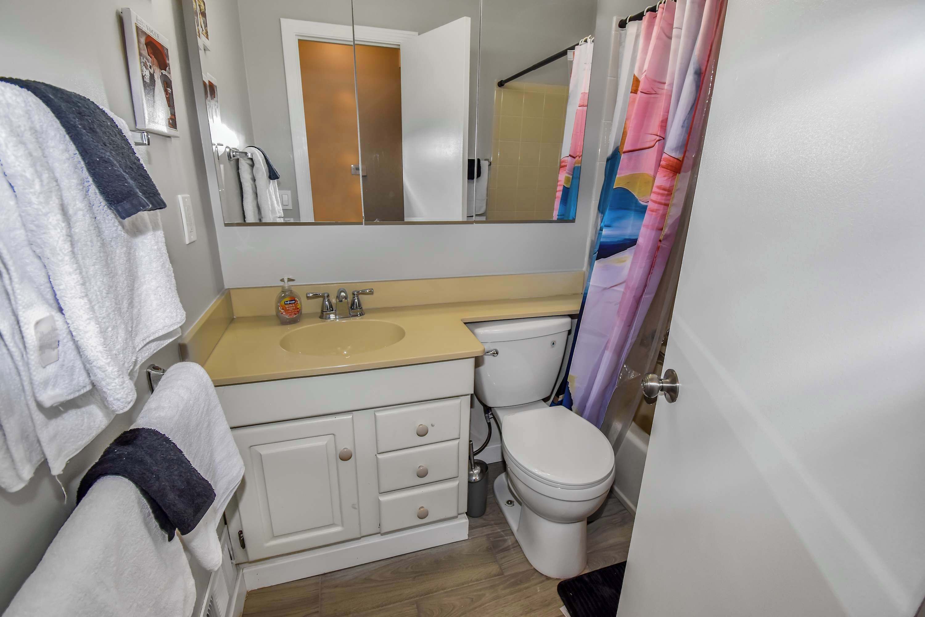 Un baño con un lavabo beige, un inodoro blanco y un espejo sobre el lavabo.
