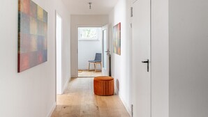 A hallway with a wooden floor, a round orange ottoman, and a chair in the background. - Fantastisch im Naturpark Altmühltal (Greding)