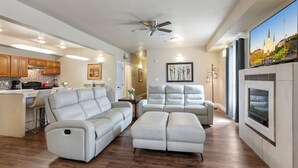 A spacious living area with a kitchen, a fireplace, and a large TV screen. - 20% OFF Monthly | 10% OFF Weekly-Spacious and Fully Furnished Condo Near St. Charles (New Orleans)