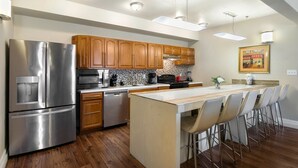 A modern kitchen with stainless steel appliances, wooden cabinets, and a central island with bar stools. - 20% OFF Monthly | 10% OFF Weekly-Spacious and Fully Furnished Condo Near St. Charles (New Orleans)