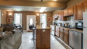 A modern kitchen with wooden cabinets, stainless steel appliances, and a central island. - 20% OFF Monthly | 10% OFF Weekly-St. Charles Ave Condo – Minutes to FQ (New Orleans)