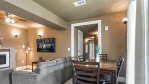 A modern living room with a sectional sofa, a wooden dining table with chairs, a fireplace, and a ceiling fan. - 20% OFF Monthly | 10% OFF Weekly-St. Charles Ave Condo – Minutes to FQ (New Orleans)
