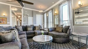 A modern living room with a sectional sofa, a round coffee table, and a ceiling fan.