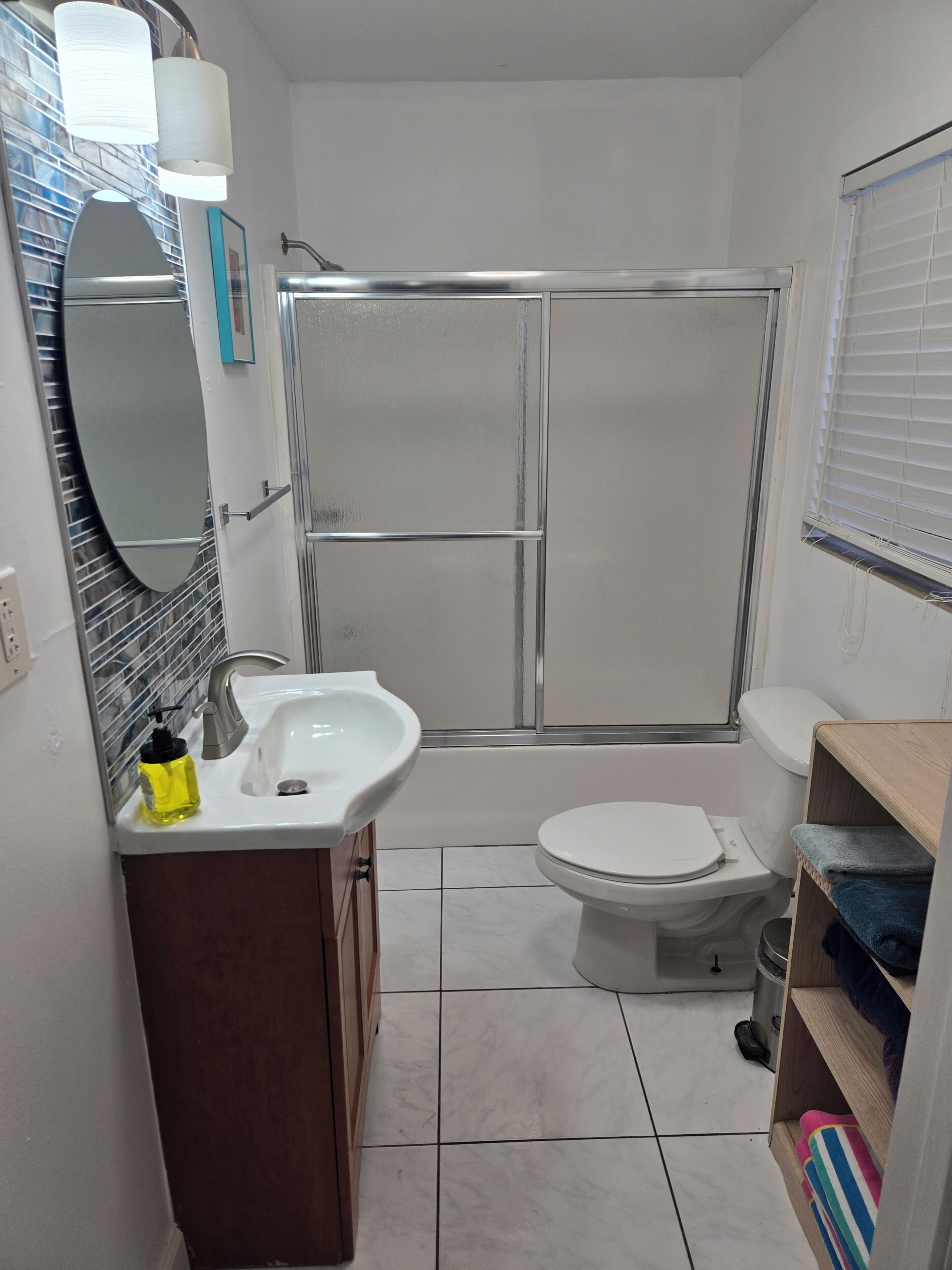 Et badeværelse med bruser, toilet, vask og spejl.