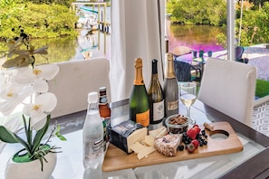 A table with a cheese board, wine bottles, a bottle of water, and a plant. - 2/1 Waterfront Apt. Large Dock In 1 of W Florida's most desirable neighborhoods (Palm Harbor)