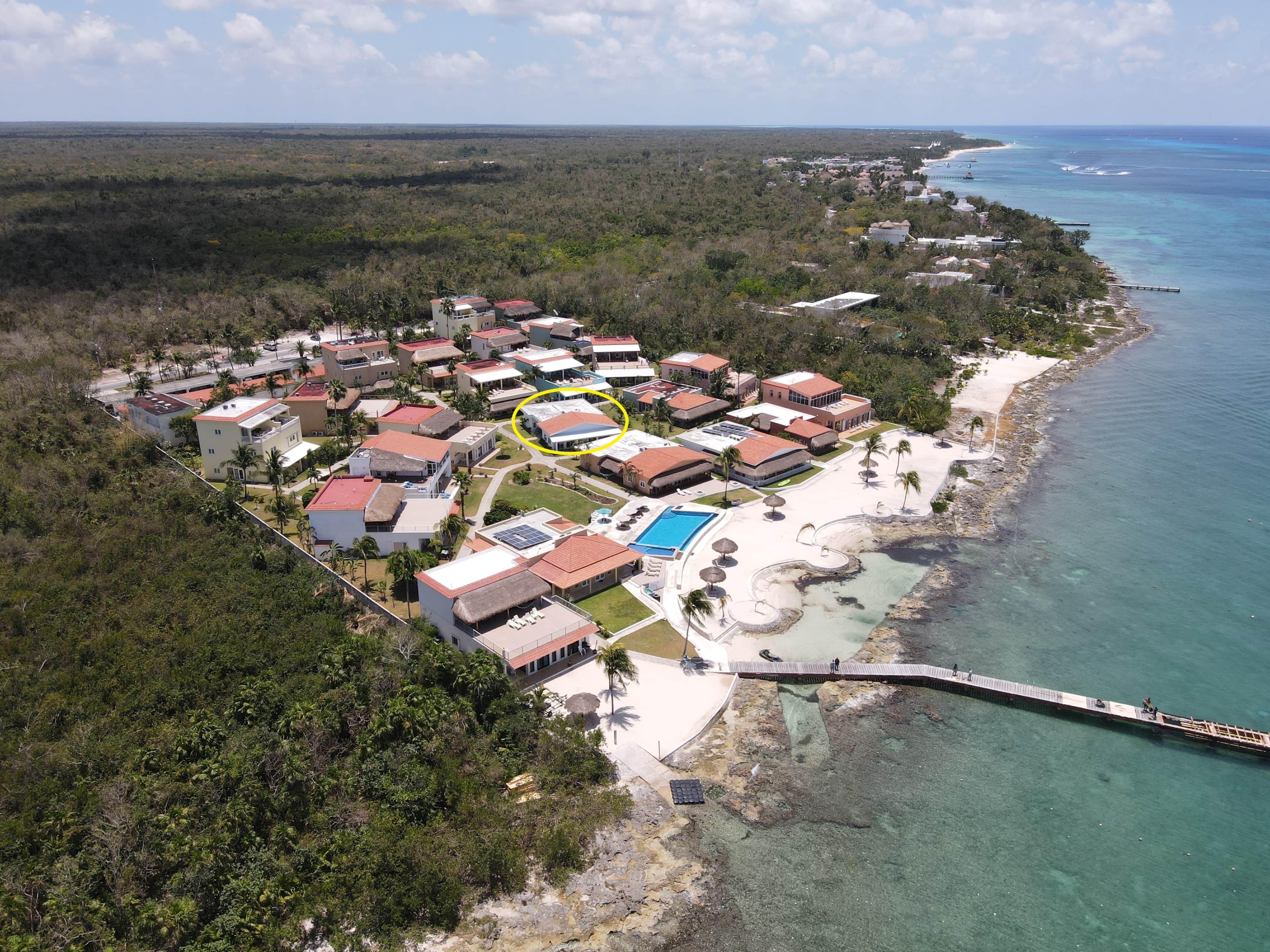 Eine Vogelperspektive eines Küstenresorts mit mehreren Gebäuden, einem Schwimmbad und einer Pier, die sich in den Ozean erstreckt.