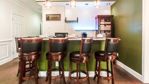 A bar area with four stools, a countertop with bar tools, and a sign that reads "BILLIARD LOUNGE".