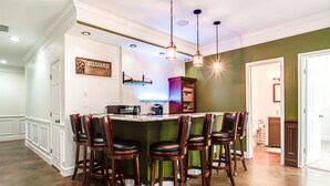 A kitchen with a bar area, bar stools, and a sign for 'Billiard Lounge'.