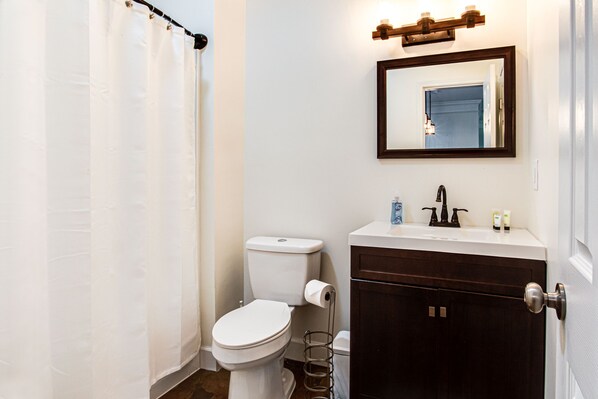 A bathroom with a toilet, sink, and mirror.