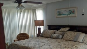 A bedroom with a large bed, a ceiling fan, a chair, a lamp, and a painting on the wall. - Clean spacious 2BR mobile home in great senior community in Largo Florida (Largo)