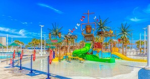 Ein Wasserpark mit einer großen, grünen Wasserrutsche, einem Poolbereich und Palmen.