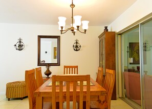 Un coin repas comprenant une table en bois, des chaises, un lustre et un buffet.