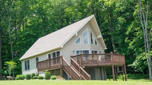 A two-story house with a deck and stairs leading to a covered porch.