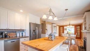 A modern kitchen with white cabinets, stainless steel appliances, and a wooden island.