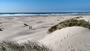 A wide sandy beach with dunes and the ocean in the background.