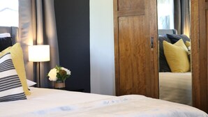A hotel room with a neatly made bed, a bedside lamp, a vase with flowers, and a wooden wardrobe. - Abercrombie Ridge - Lux LODGE and Spa Retreat - Pet-friendly (Curraweela)